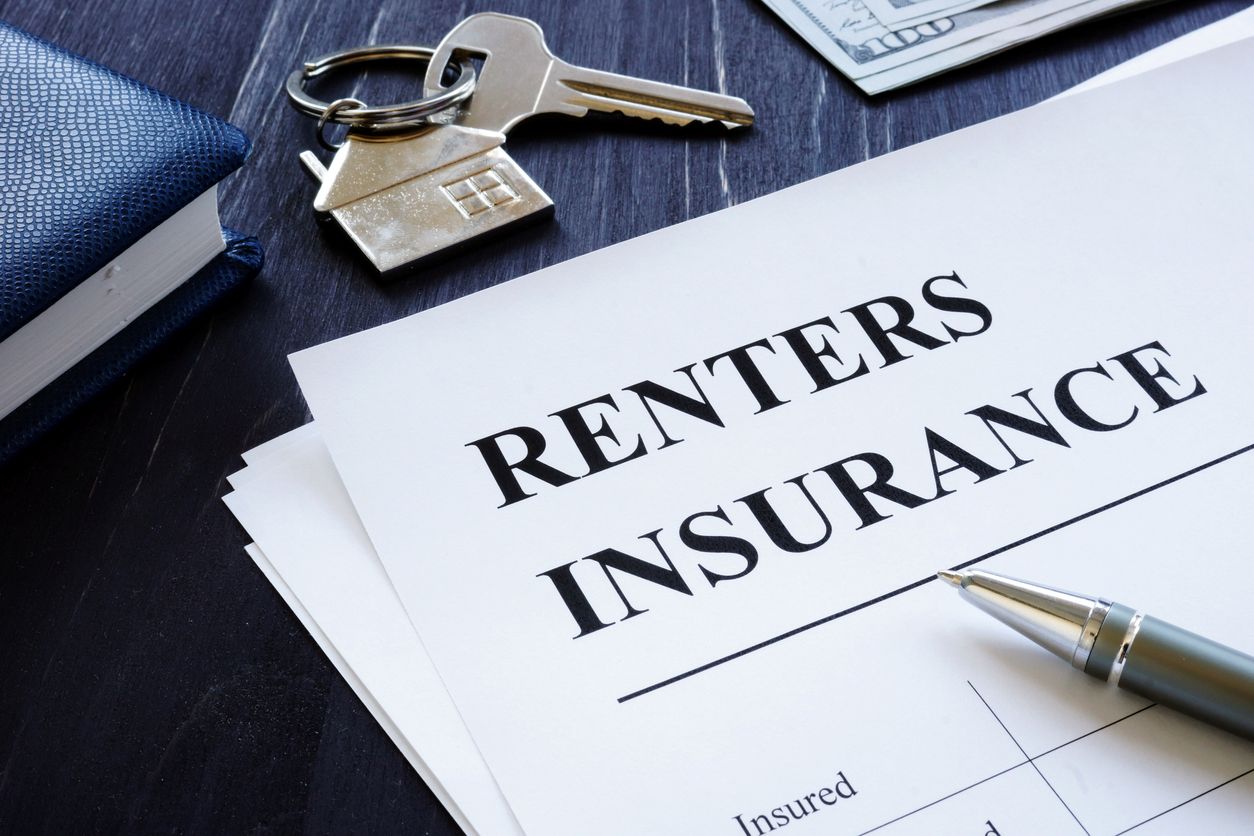 A renters insurance policy agreement sitting next to keys for an apartment.