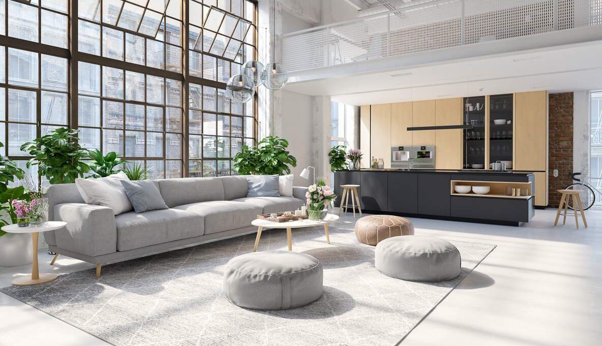 A spacious luxury apartment with massive windows and neutral colored furniture.
