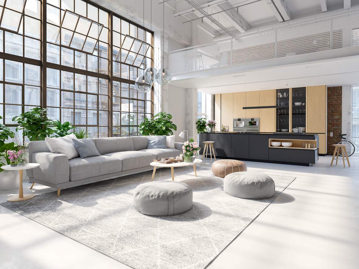 A spacious luxury apartment with massive windows and neutral colored furniture.