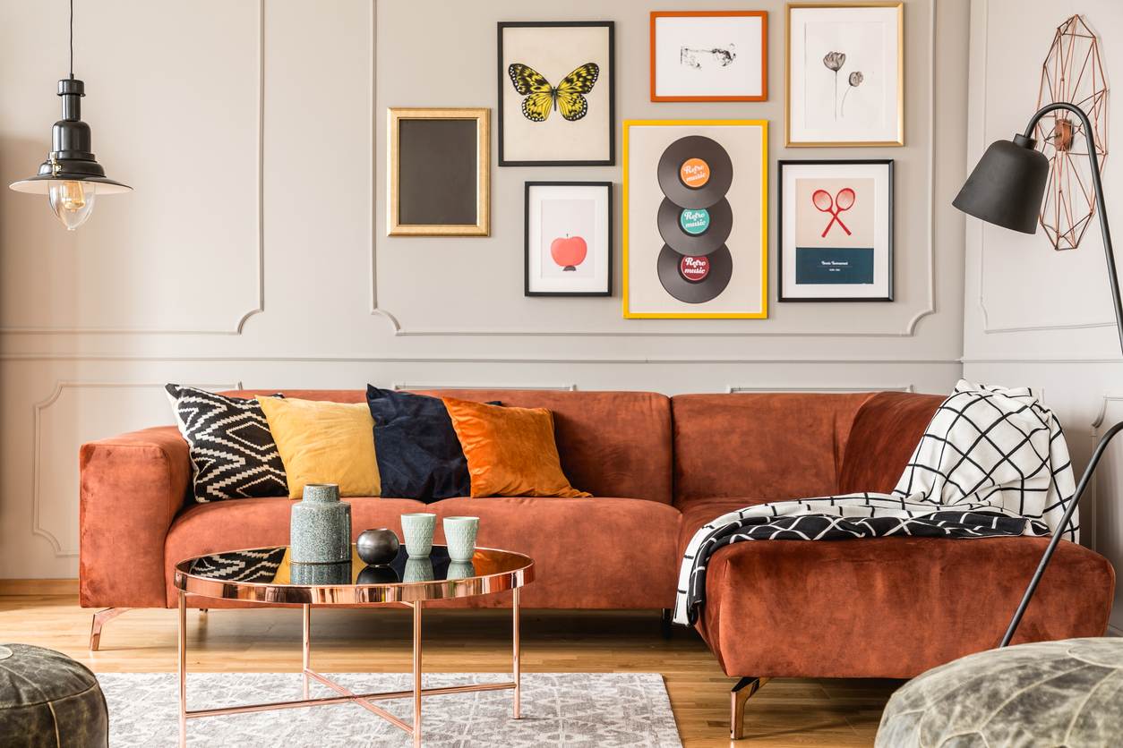 Eclectic style living room with funky art on the walls, an orange couch, and warm toned pillows.
