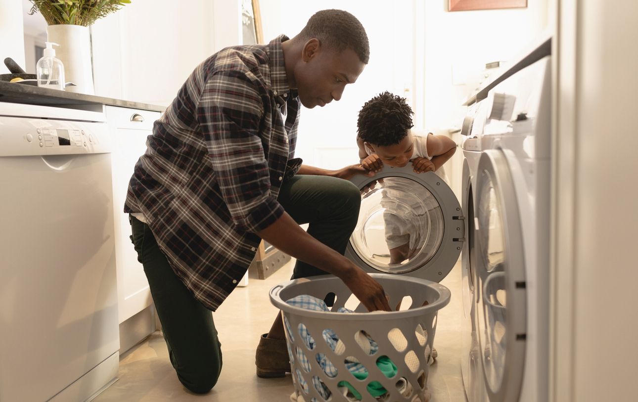 A father and son do laundry together in their apartment.