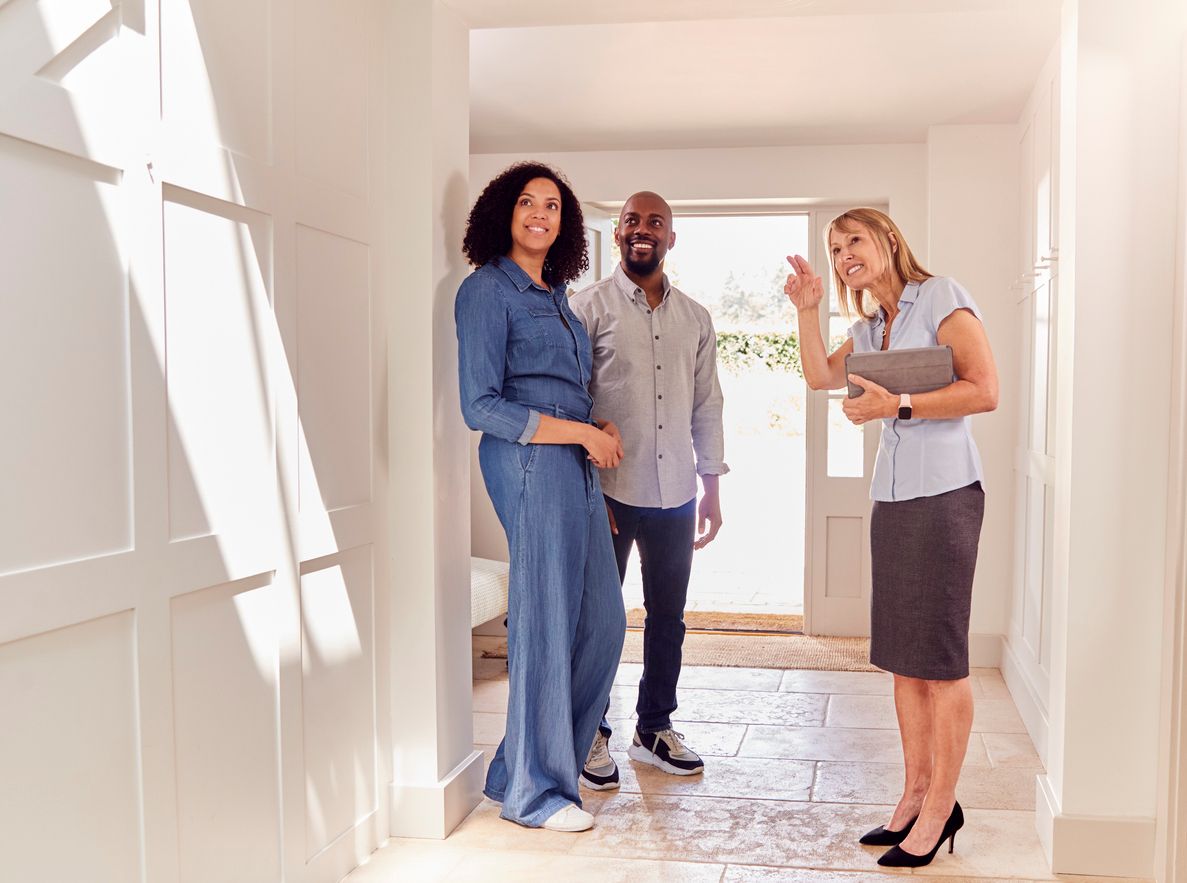 A happy couple smiles as they tour an apartment with a leasing agent.