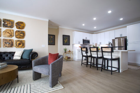 Bright living room at Relay 129 in Liberty Township featuring open-concept layout, large windows, modern finishes, and seamless flow into the kitchen with matte black hardware accents.