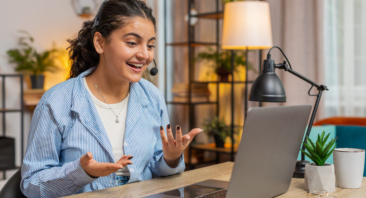 A woman talks to her coworkers while working from home in her apartment.