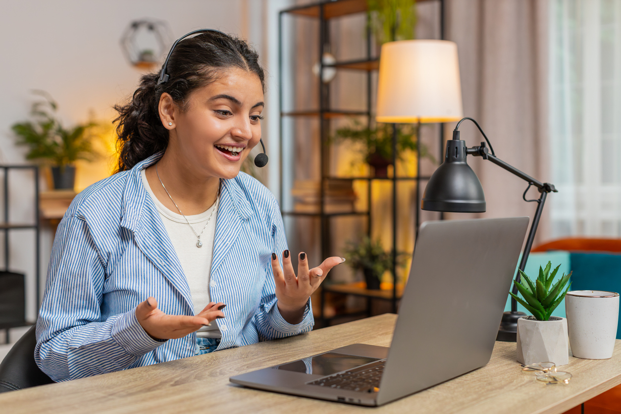 A woman talks to her coworkers while working from home in her apartment.