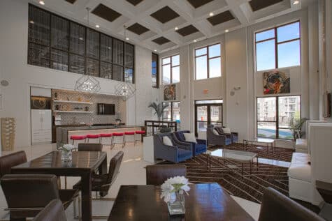 Stylish resident clubhouse at Allure Apartments with modern bar seating, geometric pendant lights, lounge areas, and entertainment spaces.