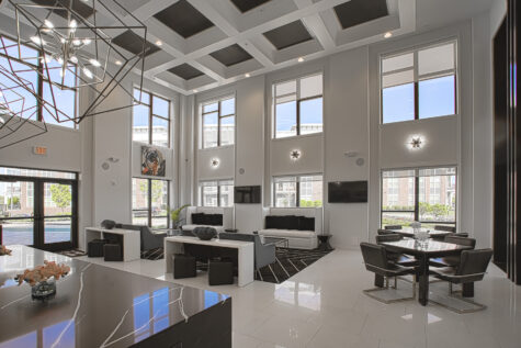 Luxury clubhouse lounge at Allure Apartments with soaring ceilings, geometric light fixtures, black-and-white décor, and contemporary seating areas.