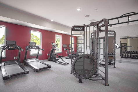 Modern fitness center with treadmills, cardio machines, strength-training equipment, and large windows at Relay 129 by HILLS Properties in Liberty Township, Ohio.