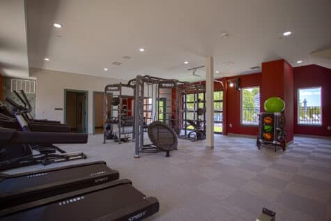Spacious community fitness studio featuring cardio equipment, functional training stations, free weights, and poolside views at Relay 129 by HILLS Properties in Liberty Township, Ohio.