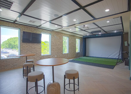 Resident entertainment lounge with TruGolf simulator, café-style seating, and modern finishes at Relay 129 by HILLS Properties in Liberty Township, Ohio.