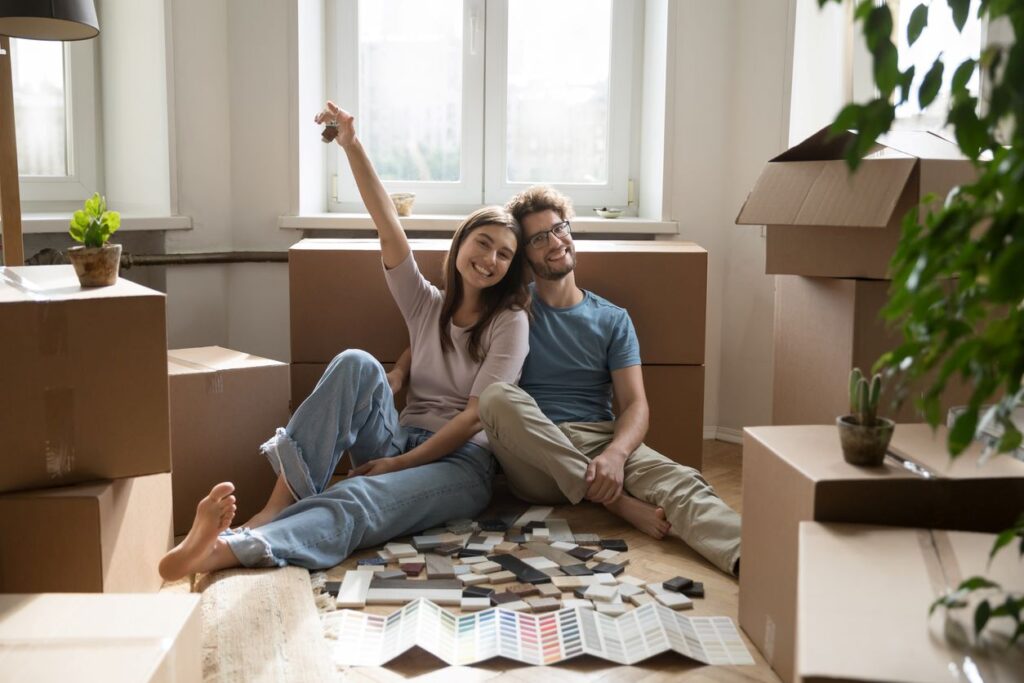 A man and woman relax in their new home surrounded by boxes.
