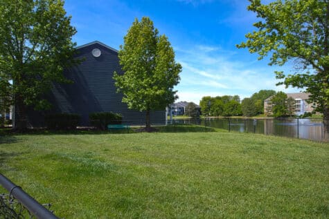 Spacious fenced dog park at Emerald Lakes in Greenwood, Indiana, featuring open green space, mature trees, and scenic lake views for resident pets at this HILLS Properties community.