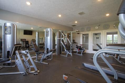 Fitness center at Emerald Lakes in Greenwood, Indiana, featuring cardio machines, strength-training equipment, mirrored walls, and a modern resident workout space by HILLS Properties.