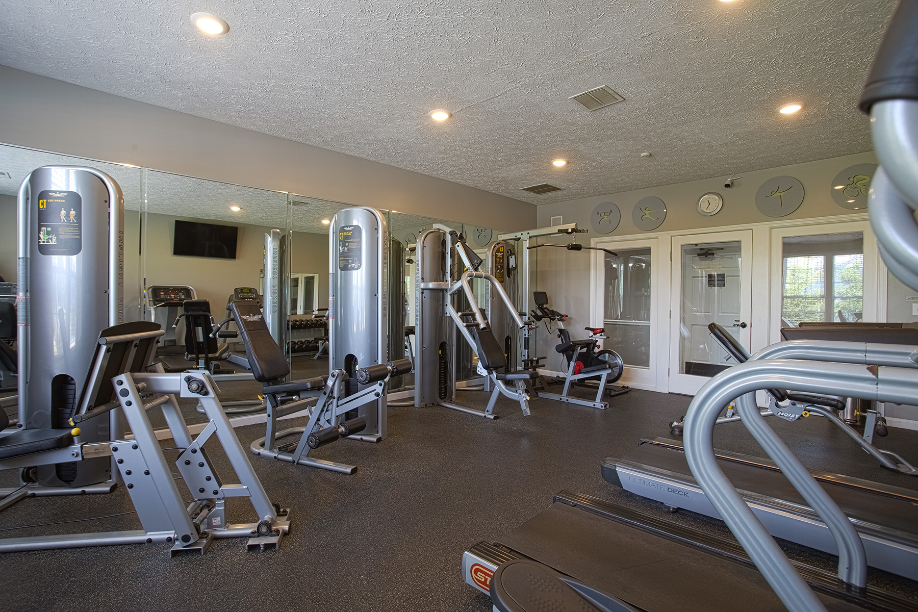 Fitness center at Emerald Lakes in Greenwood, Indiana, featuring cardio machines, strength-training equipment, mirrored walls, and a modern resident workout space by HILLS Properties.