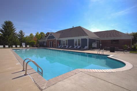 Outdoor community pool at Emerald Lakes in Greenwood, Indiana, with expansive sundeck areas, lounge chairs, and modern clubhouse surroundings for resident relaxation by HILLS Properties.