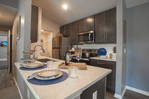 Kitchen with breakfast bar seating, quartz countertops, dark wood cabinetry, and an adjoining dining area in the Island floor plan.