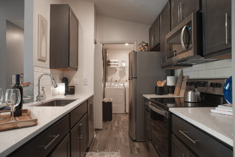 Updated kitchen at Island Club Apartments showcasing stainless steel appliances, quartz countertops, subway tile backsplash, and modern finishes.