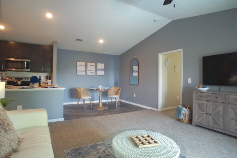 Spacious living room in The Island floor plan at Island Club Apartments featuring plush carpeting, vaulted ceilings, and sliding glass doors that fill the home with natural light.