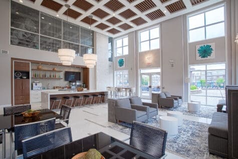 Spacious resident clubhouse and café area at Savoy at the Streets of West Chester in West Chester, Ohio, with high ceilings, modern seating, kitchen bar, and stylish community gathering spaces by HILLS Properties.