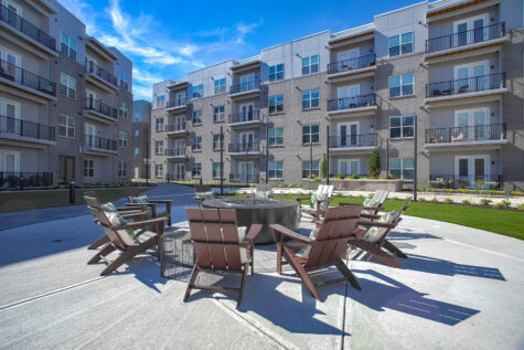 Inviting courtyard at Vantage Anderson by HILLS Properties in Anderson, Ohio, showcasing Adirondack seating around a community fire pit with landscaped green space and contemporary apartment homes.
