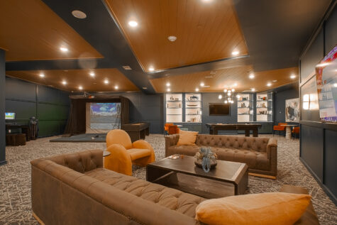 Spacious resident clubhouse at Vantage Anderson in Anderson, Ohio, featuring comfortable lounge seating, a pool table, built-in shelving, and a golf simulator entertainment area by HILLS Properties.