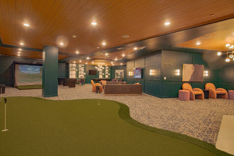 Alt text: Entertainment lounge at Vantage Anderson by HILLS Properties in Anderson, Ohio, featuring an indoor putting green, golf simulator, comfortable lounge seating, large TVs, and modern resident gathering spaces.