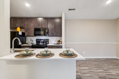Kitchen with breakfast bar seating, quartz countertops, dark wood cabinetry, and an adjoining dining area in the Hunter floor plan.