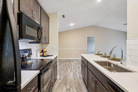 Kitchen with stainless-style finishes and direct access to a full-size in-home laundry room.