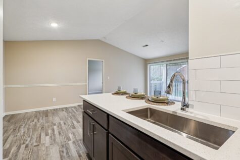 Open kitchen layout with breakfast bar, modern finishes, and sightlines into the spacious living and dining area.