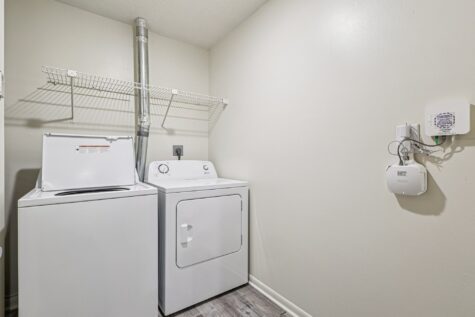 Convenient in-home laundry room with full-size washer and dryer and additional storage shelving.