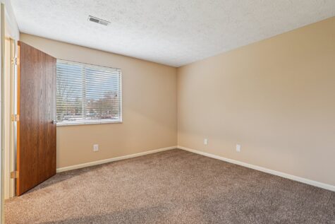Spacious secondary bedroom in the Hunter floor plan featuring plush carpeting, neutral paint colors, and a large window.