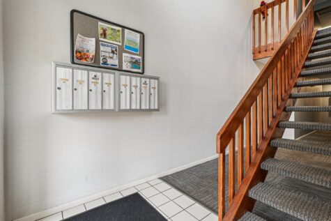 Apartment building entry at Fox Chase North Apartments featuring secured mailboxes, updated flooring, and a staircase leading to upper-level homes.