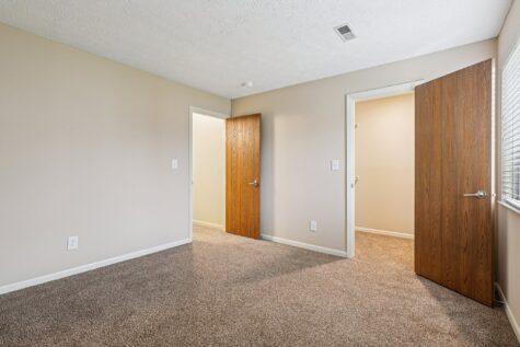Secondary bedroom with abundant natural light, plush carpeting, and easy access to nearby closets and bathrooms.
