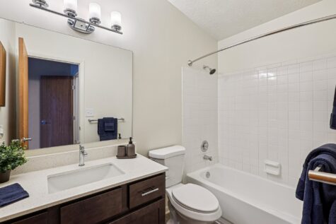 Private en-suite bathroom featuring a quartz vanity, modern cabinetry, updated fixtures, and a tub/shower combination.