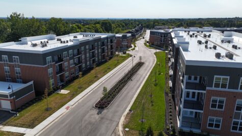 Aerial view of the main boulevard at Relay 129 Apartments and Townhomes in Liberty Township, Ohio, showcasing modern apartment buildings, landscaped streetscapes, and tree-lined sidewalks.