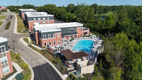 Drone view of the clubhouse and resort-style pool at Relay 129 Apartments and Townhomes in Liberty Township, Ohio, surrounded by landscaped grounds, luxury apartment buildings, and mature trees.