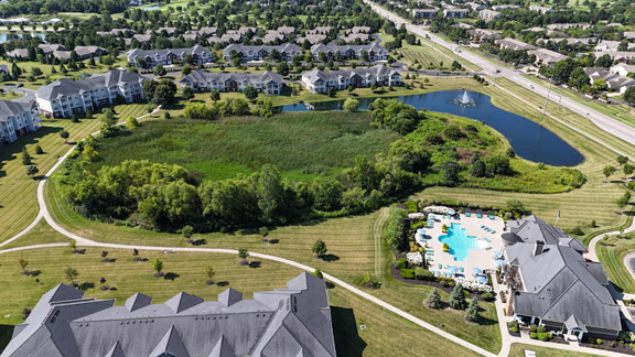 Aerial view of Palmera Apartments in Mason, Ohio, featuring the resort-style swimming pool, scenic walking trails, ponds, and expansive natural green space.