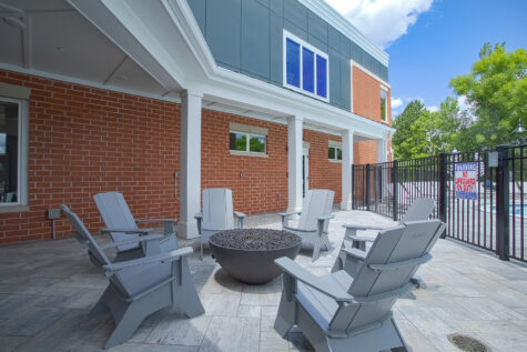 Modern outdoor social deck with fire pit at Relay 129 Apartments and Townhomes featuring pergola-covered seating, contemporary furnishings, and resort-inspired amenities.