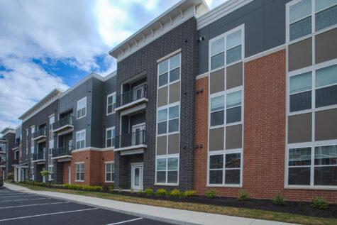 Contemporary apartment building at Relay 129 Apartments and Townhomes in Liberty Township, Ohio, featuring brick and dark-panel exteriors, private balconies, and landscaped walkways.