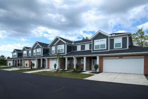 Exterior view of luxury townhomes at Relay 129 Apartments and Townhomes in Liberty Township, Ohio, featuring attached garages, welcoming front porches, and professionally landscaped grounds.