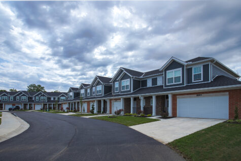Modern townhomes at Relay 129 Apartments and Townhomes in Liberty Township, Ohio, featuring attached garages, covered front porches, landscaped lawns, and a quiet residential streetscape.
