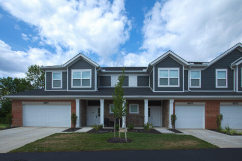 Front exterior of luxury townhomes at Relay 129 Apartments and Townhomes in Liberty Township, Ohio, highlighting modern architecture, attached garages, and tree-lined landscaping.
