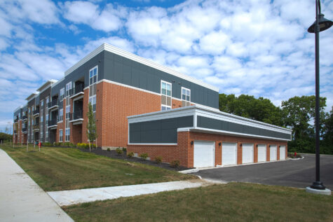 Modern apartment building and detached garage buildings at Relay 129 Apartments and Townhomes in Liberty Township, Ohio, surrounded by landscaped green space and pedestrian walkways.